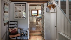 A cozy hallway with a wooden chair, a wine rack, and a framed photo collage on the wall.