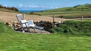 A chair and a table set on a grassy field with a stone wall and a fence.