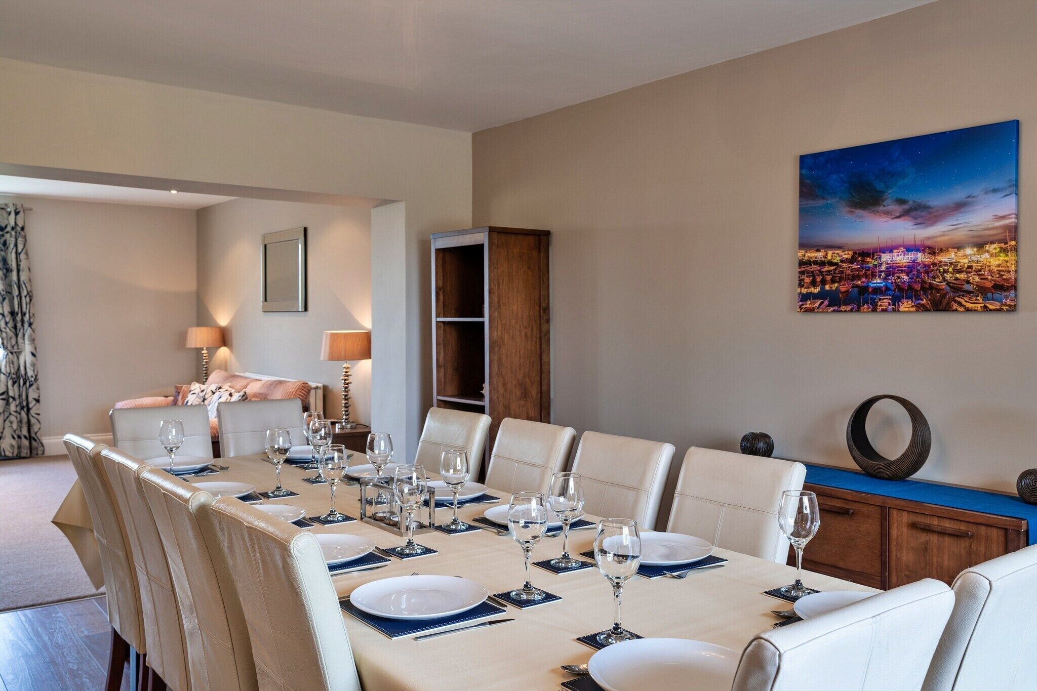 Een eethoek met een lange tafel gedekt voor zes personen, omringd door witte stoelen.