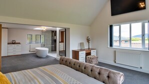 A bedroom with a large bed, a desk, a vanity, and a shower. There is a large window with a view of the outdoors. - Farmhouse in Weston near Sandy Beaches (Weston-Super-Mare)