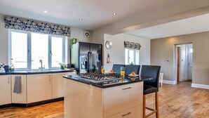 A modern kitchen with a central island, a refrigerator, and a stove. - Farmhouse in Weston near Sandy Beaches (Weston-Super-Mare)