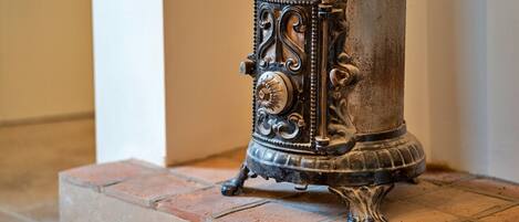 Una estufa antigua con detalles metálicos ornamentados y una perilla decorativa, sobre un piso de baldosas.