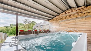A hot tub area with a wooden wall and a view of the countryside. - Barn in Wales with Swim Spa & Scenic Views (Aberystwyth)