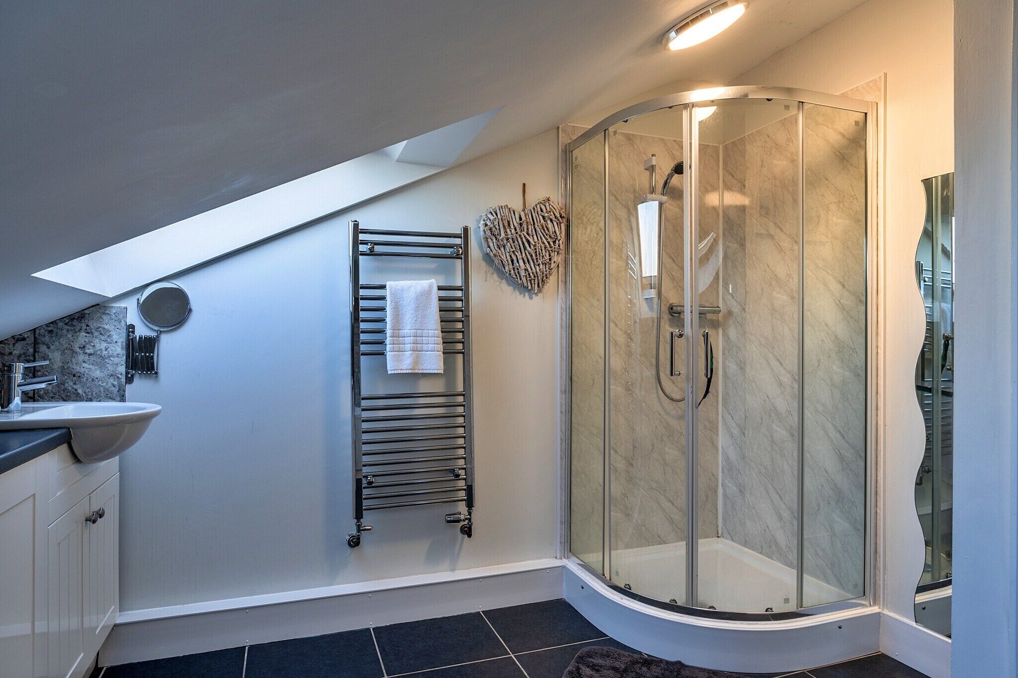 A modern bathroom with a glass shower, a towel rack, and a heart-shaped decoration.