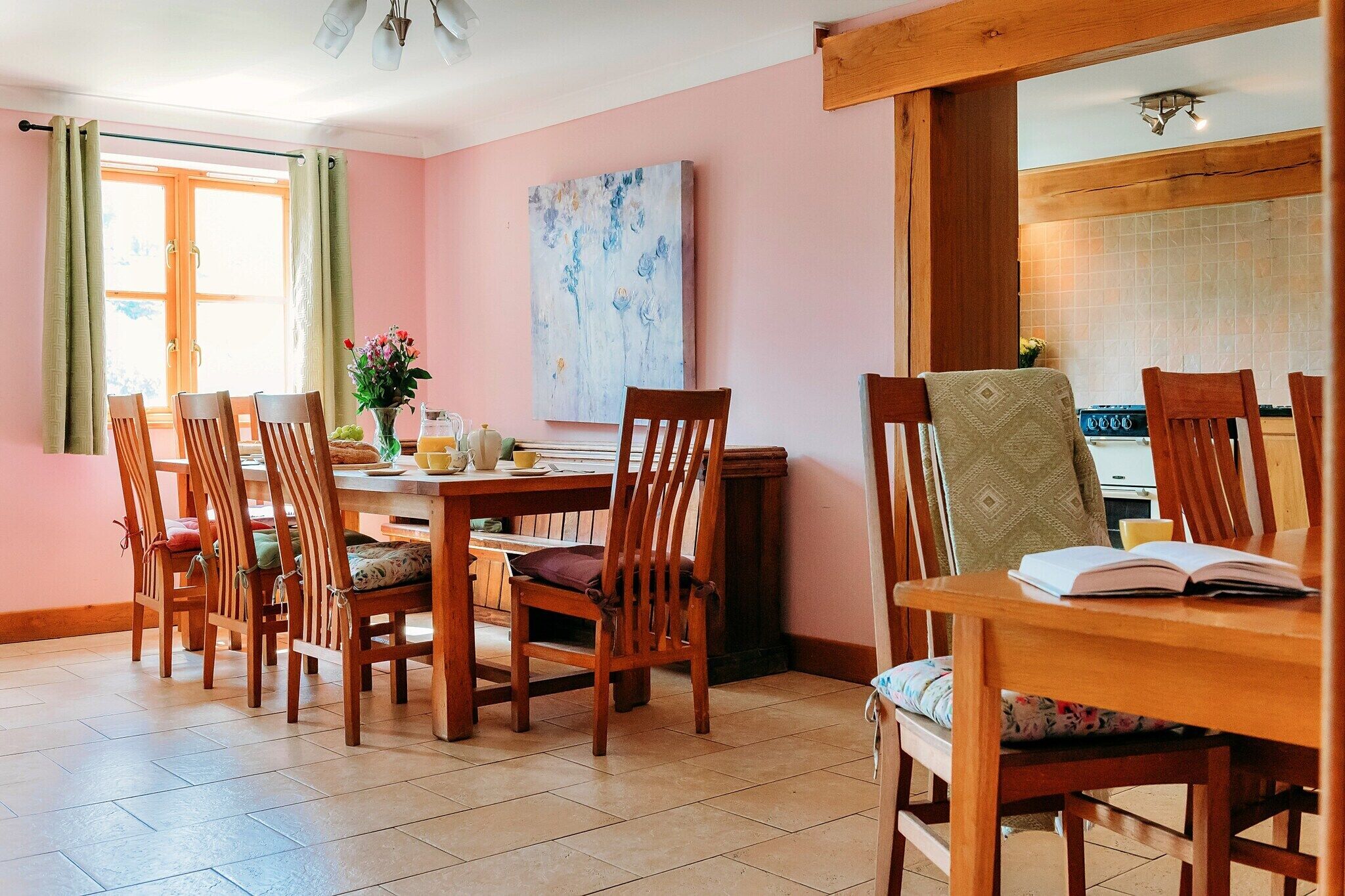 A dining area with wooden furniture, a table with a vase of flowers, and a painting on the wall.