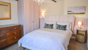 A bedroom with a bed, a wooden dresser, a chandelier, a nightstand, and a painting on the wall. - Holiday Home in Kingsand near the Beach (Kingsand)