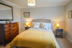 A bedroom with a bed, two bedside tables with lamps, a dresser, and a mirror on the wall. - Holiday Home in Kingsand near the Beach (Kingsand)