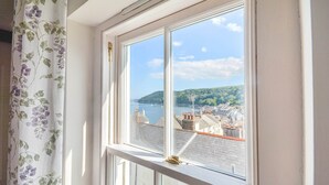 A window with a view of a coastal town, a clear sky, and a body of water. - Holiday Home in Kingsand near the Beach (Kingsand)
