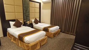 A hotel room with two beds, a large mirror, an air conditioning unit, and a curtain.