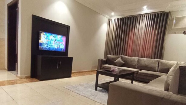 A modern living room with a flat-screen TV, a sofa, and a coffee table.