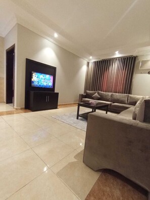 A modern living room with a flat-screen TV, a sofa, and a coffee table. - Rofahelmaskan (Abha)