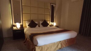 A hotel room with a large bed, two bedside tables with lamps, a headboard, and a carpeted floor.