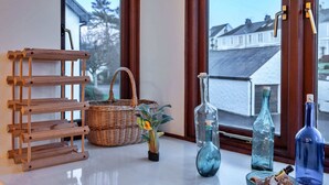 A wooden rack, wicker basket, potted plant, and glass bottles on a windowsill. - Apartment in Falmouth near Beaches & Harbour (Falmouth)