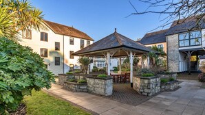 A courtyard with a gazebo, stone planters, and a well-maintained lawn. - Apartment in Falmouth near Beaches & Harbour (Falmouth)