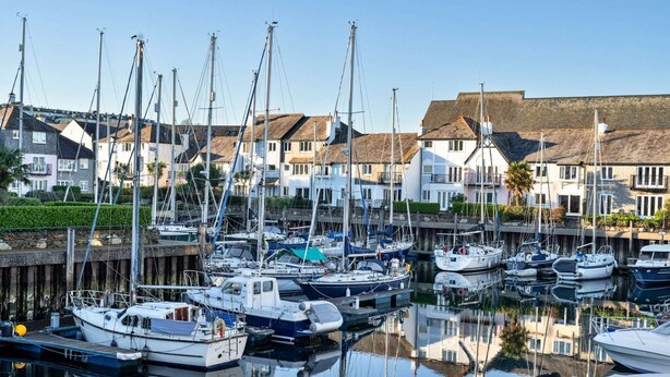 A marina with multiple boats docked, surrounded by residential buildings with thatched roofs. - Apartment in Falmouth near Beaches & Harbour (Falmouth)