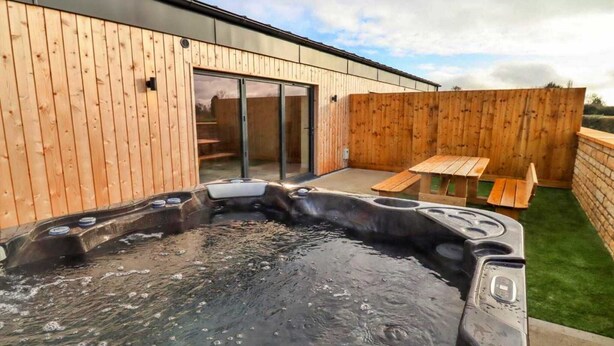Ein Whirlpool mit einer Holzterrasse und einer Terrasse mit Tisch und Stühlen.