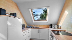 A modern kitchen with white cabinets, a wooden countertop, a built-in oven, and a skylight.
