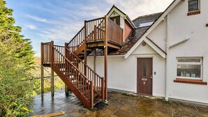 A two-story house with a wooden staircase leading to a balcony.