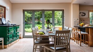 Une cuisine moderne avec un coin repas, de grandes portes-fenêtres coulissantes donnant sur un jardin et une commode verte.