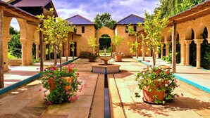 A courtyard with a central fountain, surrounded by arches and potted plants. - Loft in Cotswolds with Pool & Scenic Gardens (Kingham)