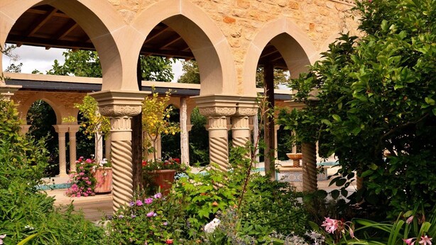 A courtyard with stone arches, lush greenery, and potted plants. - Loft in Cotswolds with Pool & Scenic Gardens (Kingham)