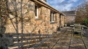 A stone building with a patio area featuring outdoor seating. - Holiday Home near Nanjizal Cove & Coastal Path (Sennen)