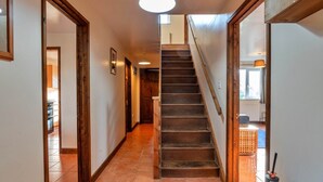 A hallway with a wooden staircase, tiled floor, and a ceiling light. - Holiday Home near Nanjizal Cove & Coastal Path (Sennen)