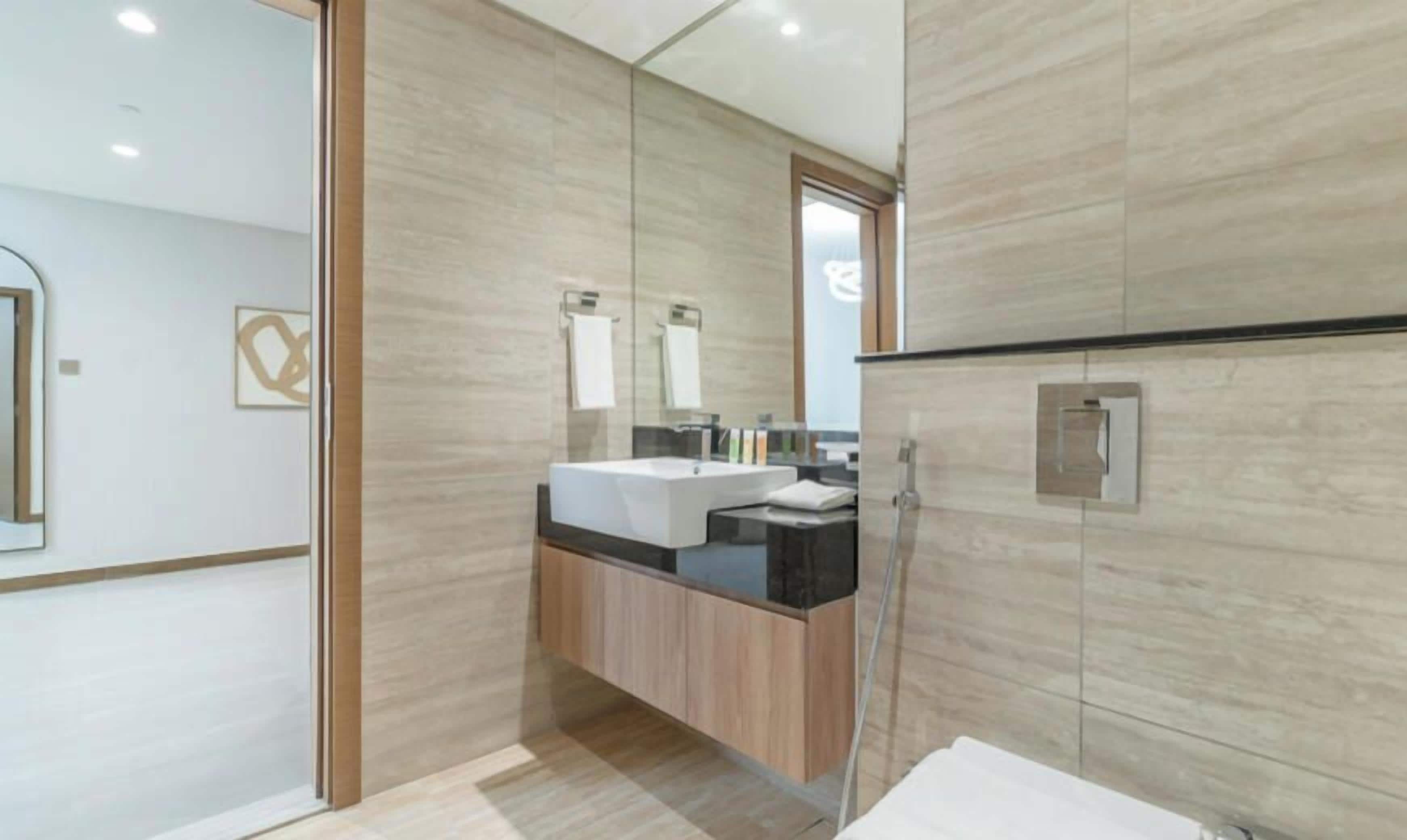 A modern bathroom with a wooden vanity, a large mirror, and a shower area.