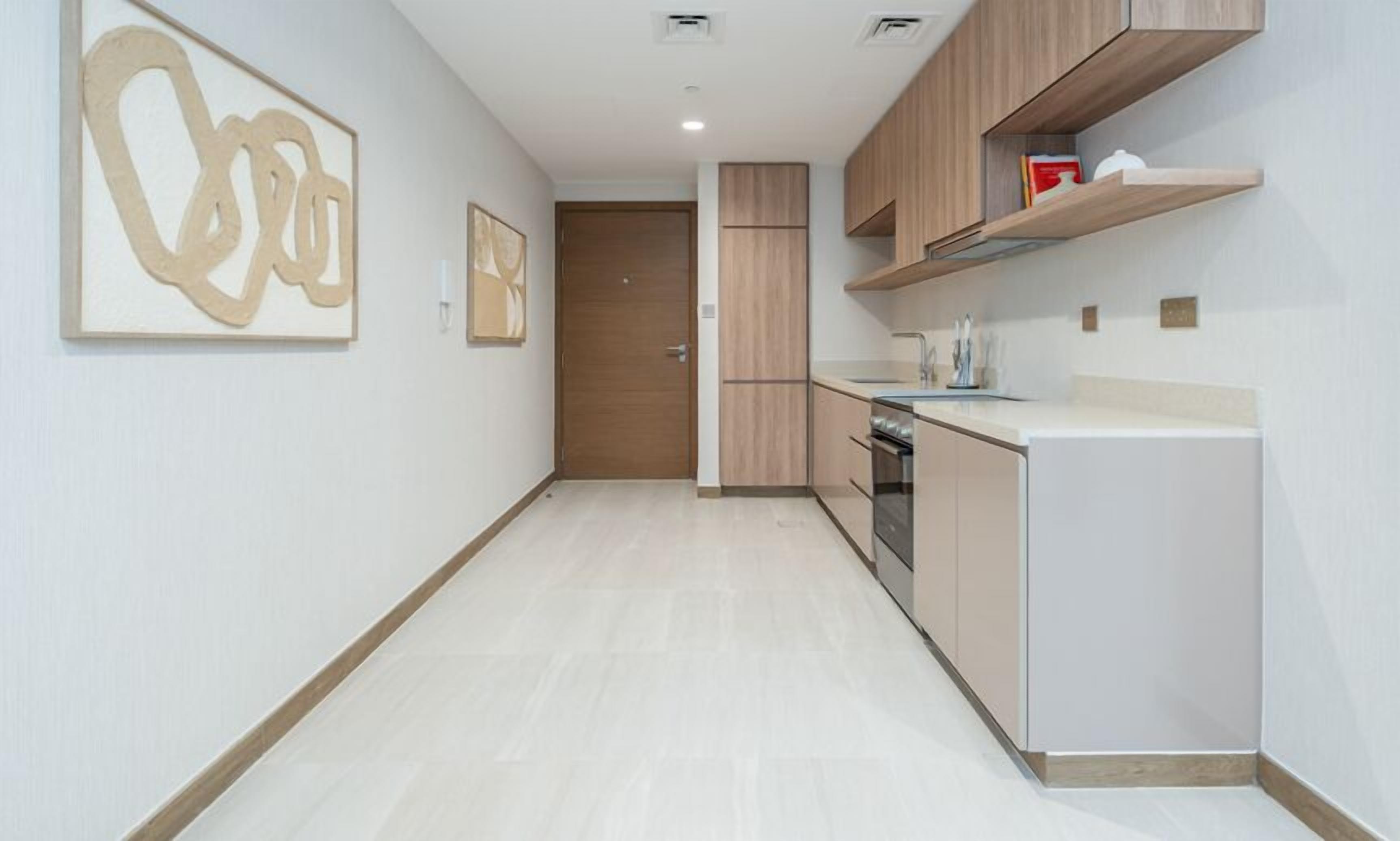 A modern kitchen with light wood cabinets, a built-in oven, and a white countertop.