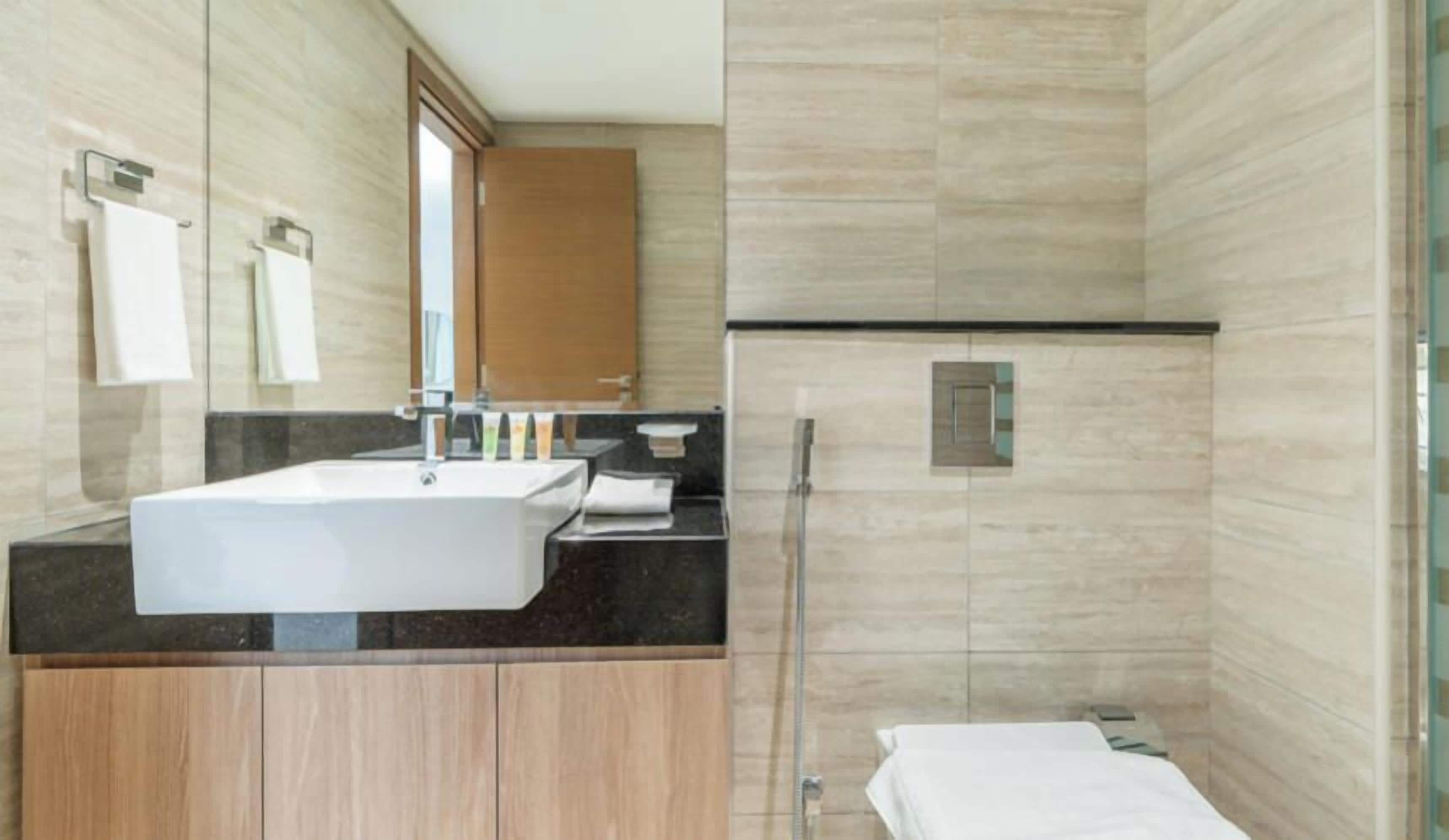 A modern bathroom with a large sink, mirror, and shower area.