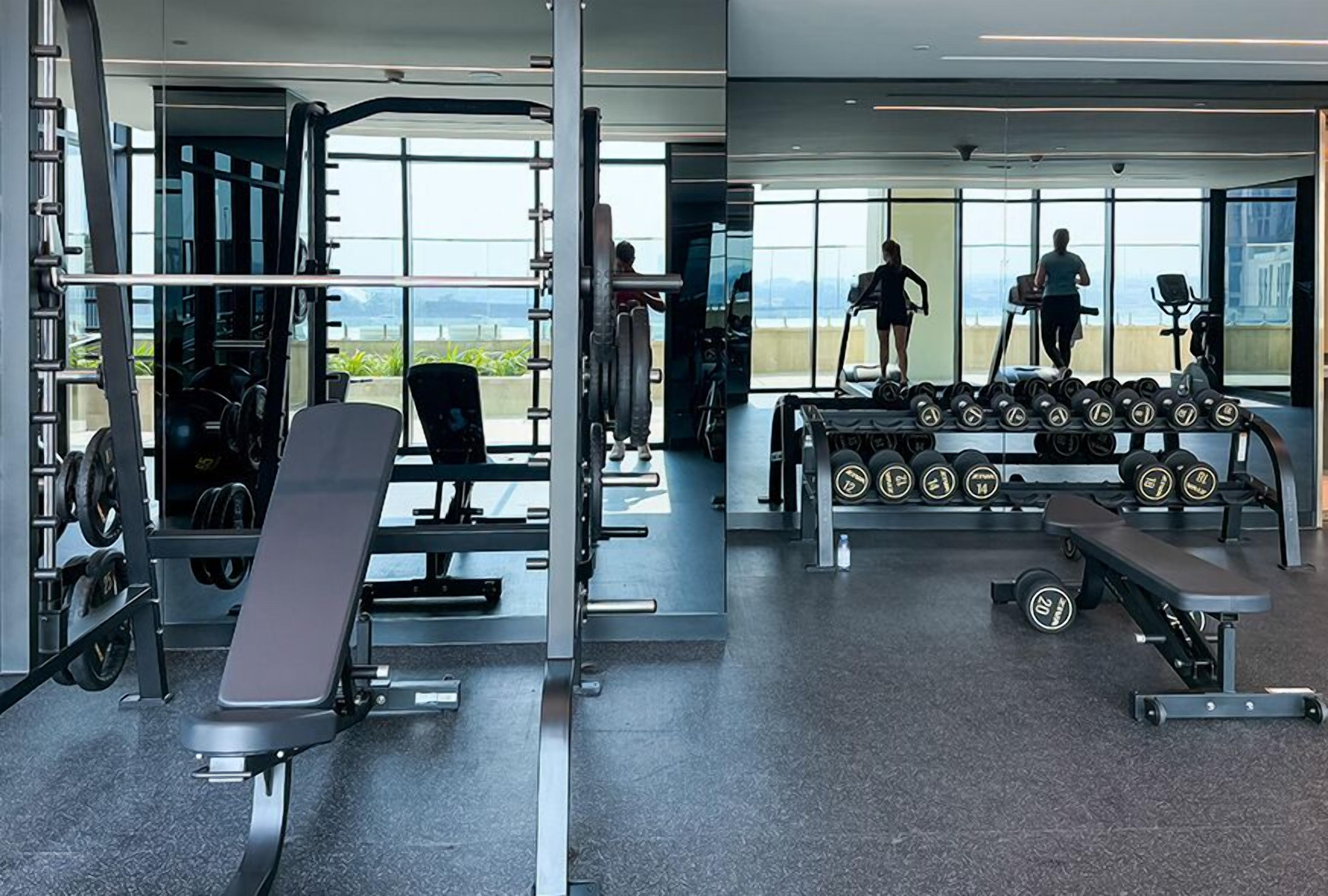 A modern gym with weightlifting equipment, treadmills, and dumbbells.