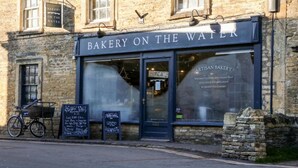 A bakery with a sign reading "Bakery on the Water" and a bicycle parked outside. - Annexe in Cotswolds near Bourton-on-the-Water (Little Rissington)
