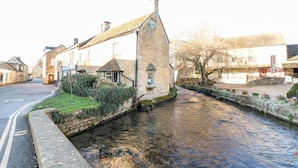 A narrow waterway with stone buildings on either side, including a prominent building with a steep roof. - Annexe in Cotswolds near Bourton-on-the-Water (Little Rissington)
