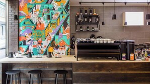 A bar area with a colorful mural, a coffee machine, and bar stools. - Tina's House & Spa (Phu Quoc)