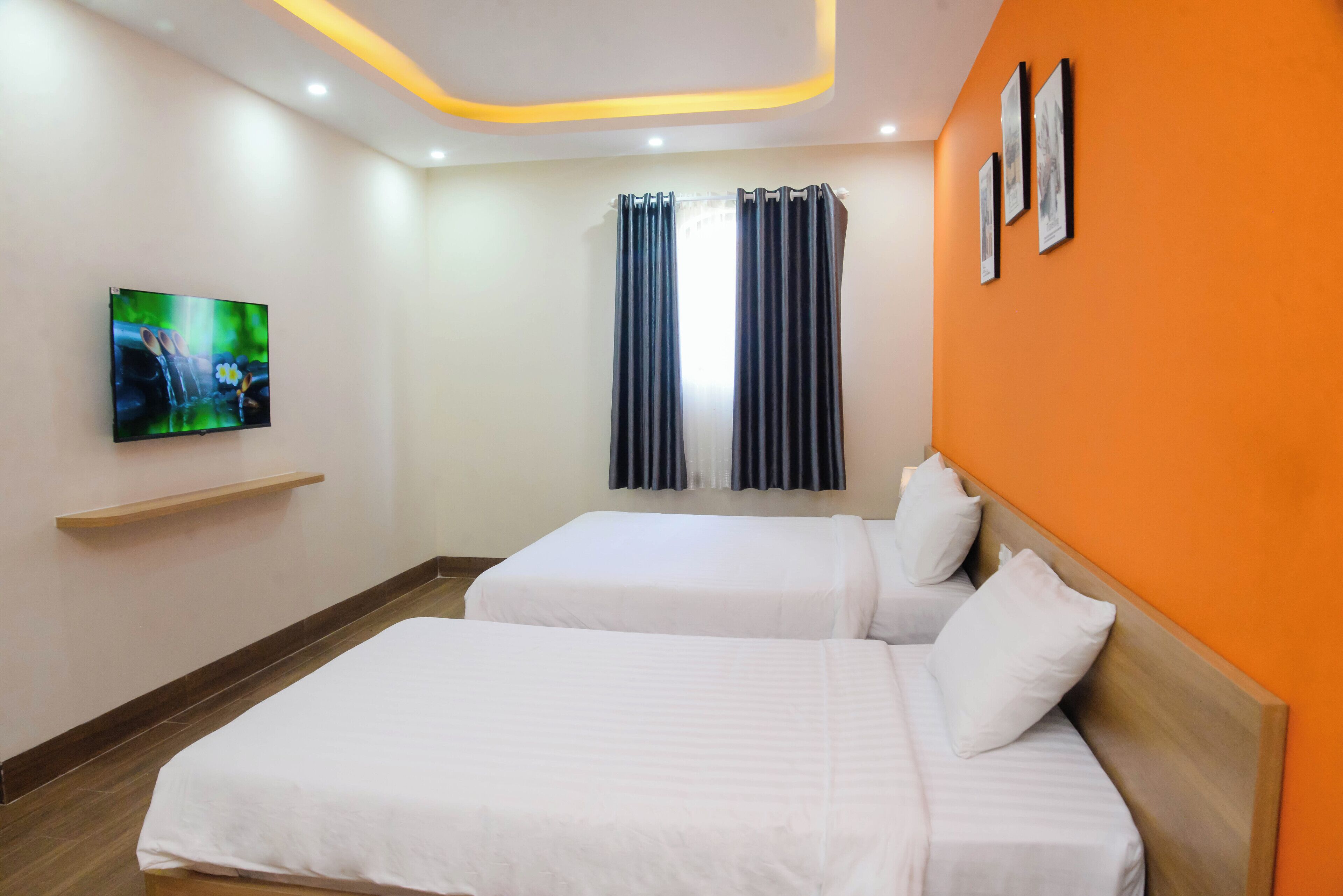 Habitación de hotel con dos camas, televisión, ventana con cortinas y una obra de arte en la pared.