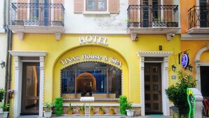 A hotel facade with a yellow exterior, a sign reading "TINA's House & Spa," and multiple potted plants in front. - Tina's House & Spa (Phu Quoc)