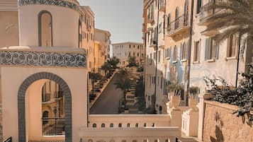 Un barrio residencial con una calle central, edificios con balcones y un arco decorativo.