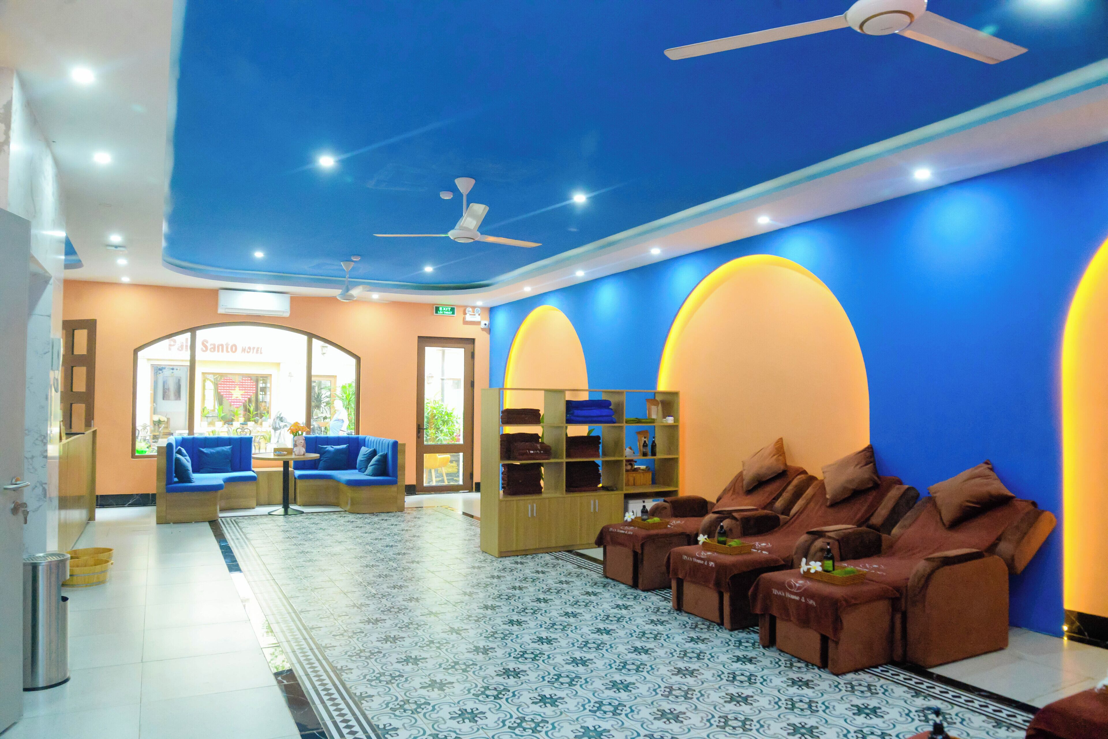 A hotel lobby with a reception area, seating, massage chairs, and a patterned floor.