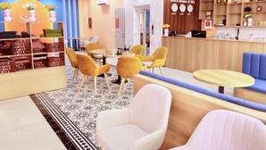 A hotel lobby with a reception desk, seating area, and a wall displaying clocks and a logo. - Tina's House & Spa (Phu Quoc)
