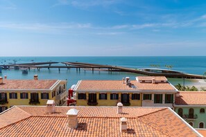A coastal view with terracotta-roofed buildings, a pier extending into the sea, and clear skies. - Tina's House & Spa (Phu Quoc)