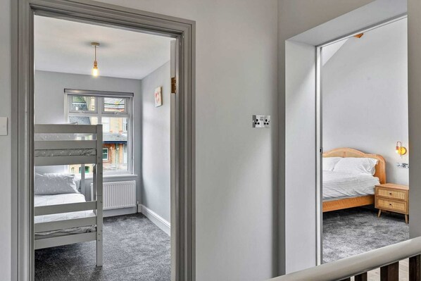 Un dormitorio con literas, una mesita de noche con lámpara y una ventana con vistas al exterior.