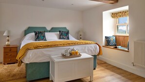 A bedroom with a bed, bedside tables, a window with a view, and a small table with a tray of orange juice. - Beautiful holiday cottage in Chittlehampton, No deposit (Llandrillo)