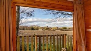 Een houten balkon met uitzicht over een veld en bomen.
