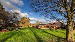 A well-maintained lawn, a large tree, and a house with a red roof. - Cottage in Norfolk near River Yare (Surlingham)