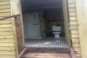 A wooden structure with a tiled floor and a white toilet.