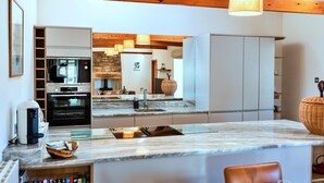 A modern kitchen with a marble countertop, built-in oven, and a large island with a sink.