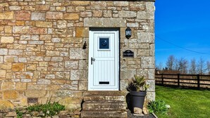 A stone building with a white door, a small step leading up to it, and a sign that reads "Old School."