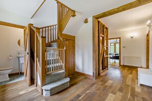 Enjoy a spacious room with a high ceiling, wooden staircase, and large window.