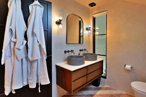 A bathroom with two sinks, a mirror, and a toilet.