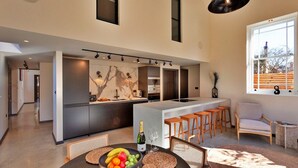 A modern kitchen with a central island, bar stools, and a seating area with a view. - Holiday Home in Kent with Hot Tub & Games Room (Appledore)